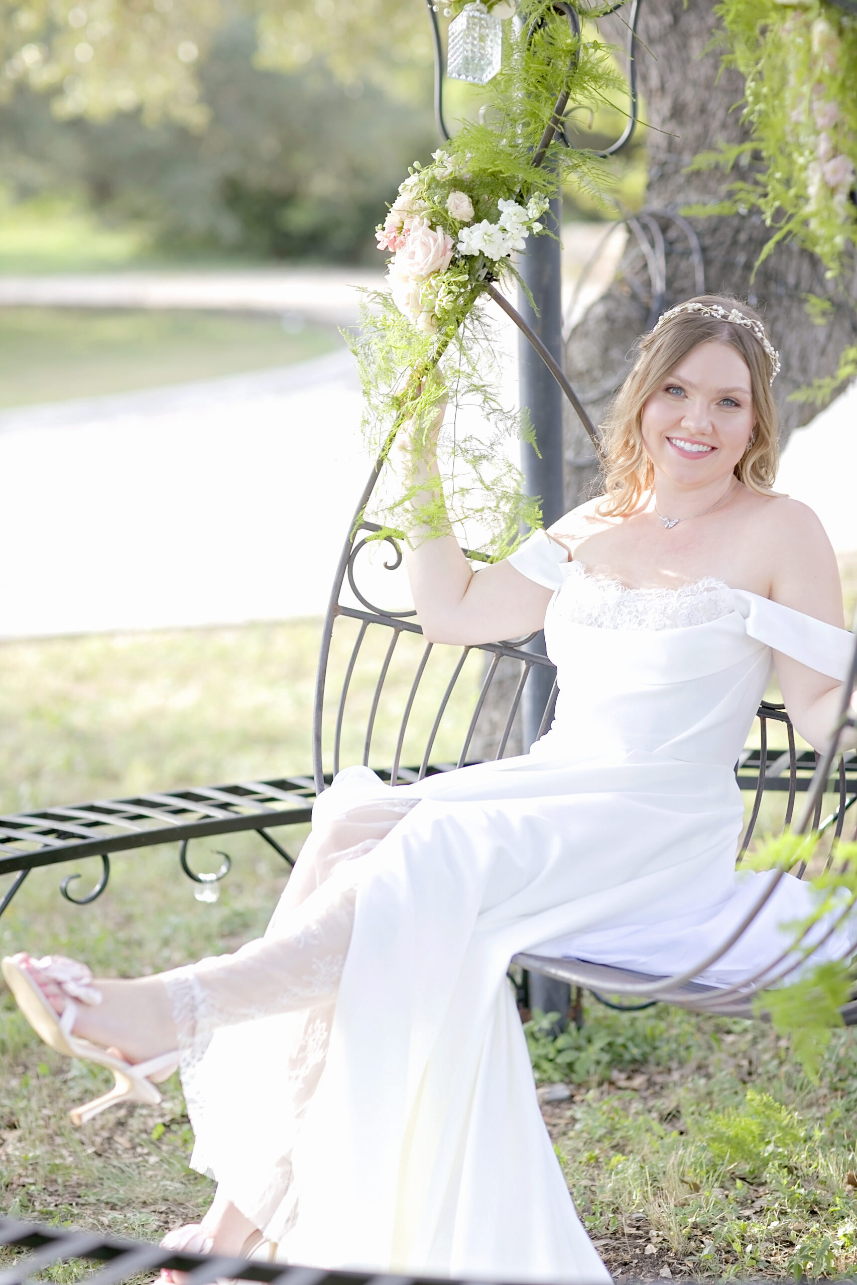 Styled wedding shoot at Oaks at Heavenly in Helotes, Texas, featuring model Lauren in a romantic white and pink Brides by Elizabeth gown, soft beige and blush florals by Julie at Oaks at Heavenly, elegant gazebo and iron swing entrance, and fall-inspired wedding décor perfect for San Antonio and Texas Hill Country wedding inspiration.