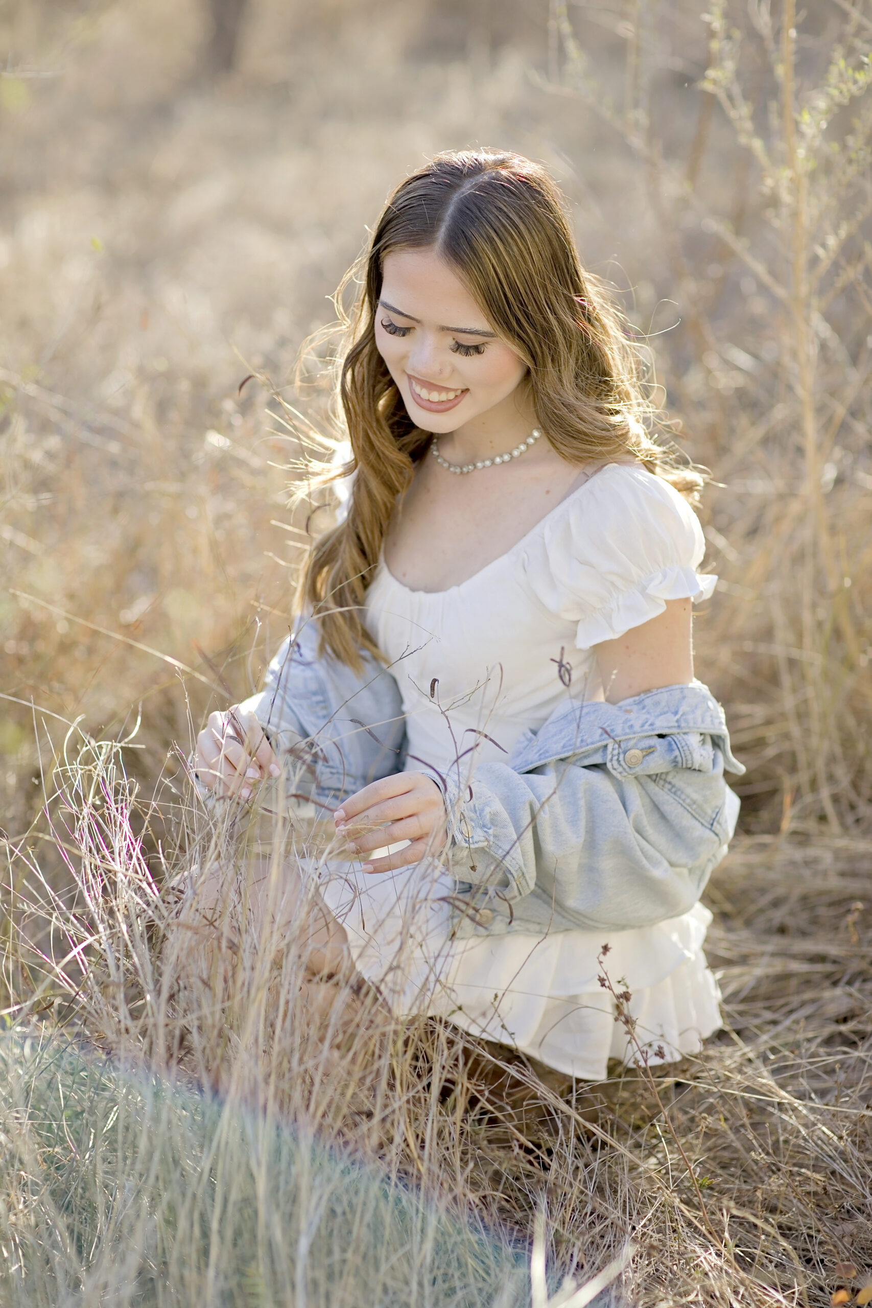 Sierra, Sotomayor High School Class of 2026 senior, posing at Government Canyon National Park in San Antonio wearing a white dress, jean jacket, and cowboy boots during her senior session.