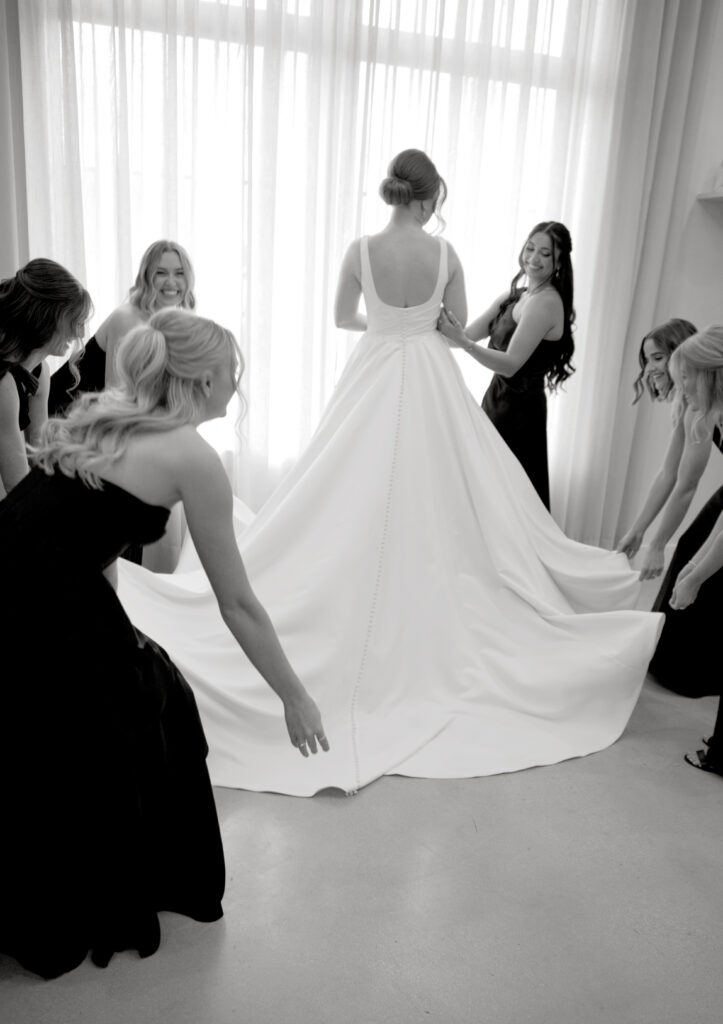 Bride with bridesmaids adjusting her wedding dress train