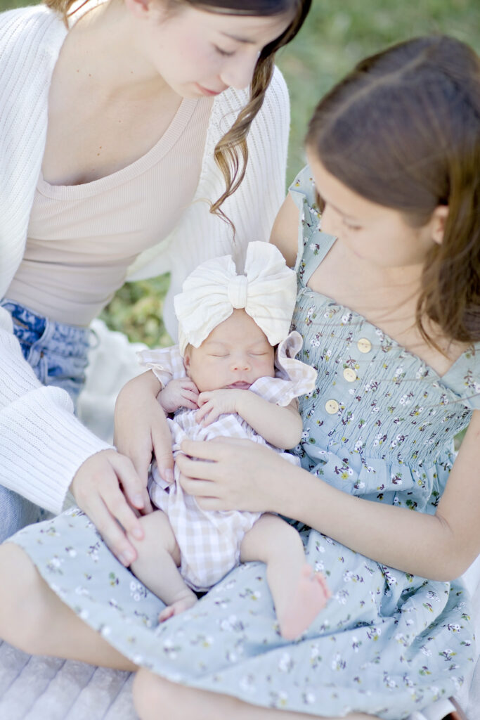 Siblings holding their newborn baby during family portraits