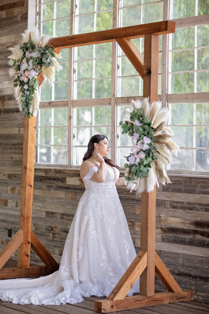 Bride beneath a floral ceremony arch at The Fields Venue in Cibolo